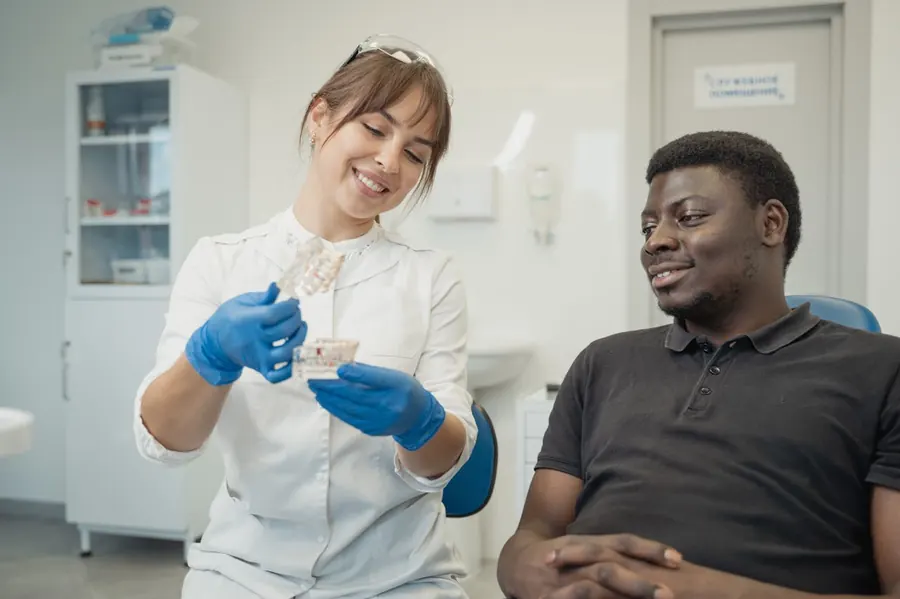 Dentist showing a dental model to a smiling patient